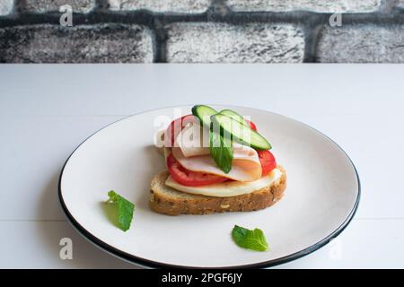 Delicious sandwich with ham, tomato, cucumber, cheese. Stock Photo