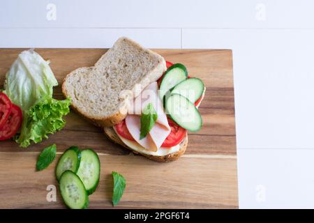 Delicious sandwich with ham, tomato, cucumber, cheese. Stock Photo