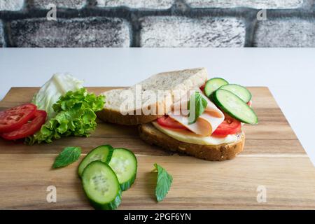 Delicious sandwich with ham, tomato, cucumber, cheese. Stock Photo