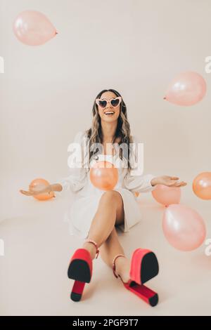 Woman Smiling Wearing Sunglasses While Throwing Balloons in Air Stock Photo