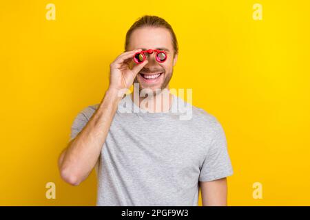 Photo of joyful optimistic man wear grey clothes have fun watching observing around isolated on yellow color background Stock Photo