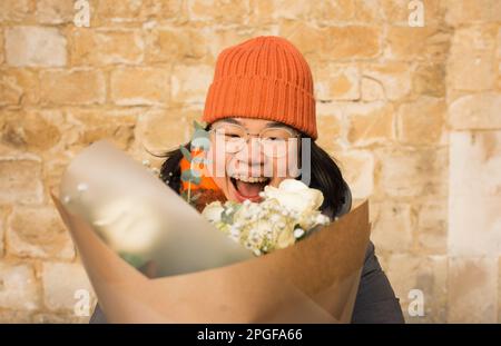 Asian woman holding a big bunch of flowers smiling Stock Photo