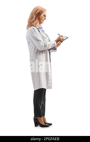 Full length profile shot of a female doctor standing and writing a document isolated on white background Stock Photo