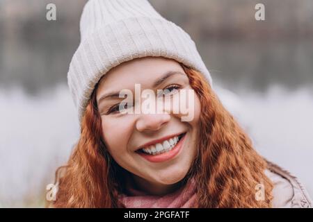 Curly redhead woman 30-35 in hat smiling Stock Photo