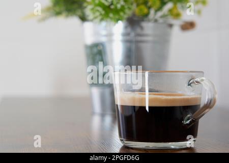Delicious cup of black coffee with foam on a wooden table Stock Photo