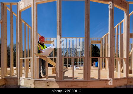 In construction process an architectural engineer checks quality of work on site using construction blueprints Stock Photo