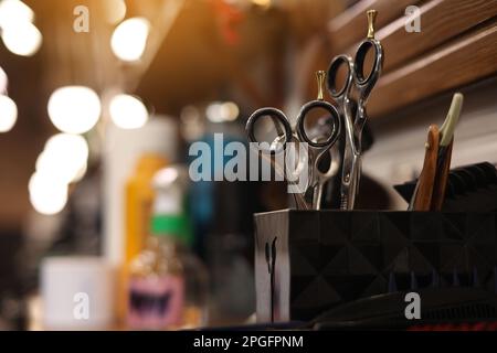Professional hairdressing tools. Various steel scissors and combs, hairbrushes on wooden table on barbers workplace at barbershop salon. The concept o Stock Photo