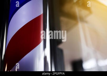 Barber pole spinning at night. International barbershop pole sign. A barber pole calling for people at street. Vintage barbershop. Salon Stock Photo