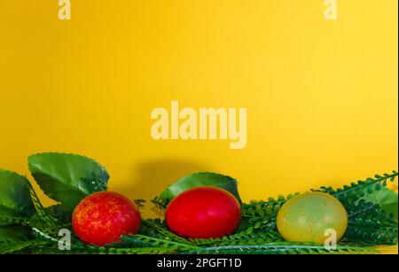 Easter egg in leaves, creative natural holiday design, yellow background Stock Photo