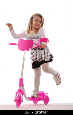 Cute little girl riding pink scooter  isolated on white backround Stock Photo