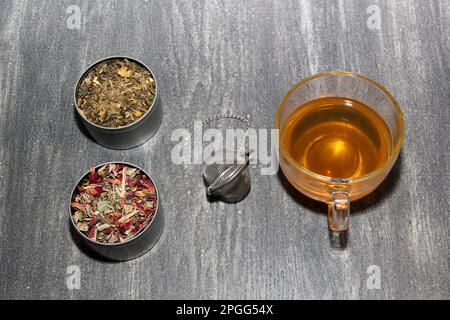 Tools for the preparation of herbal tea: glass cup, infuser, spoon, dehydrated, dried herb and sachets Stock Photo