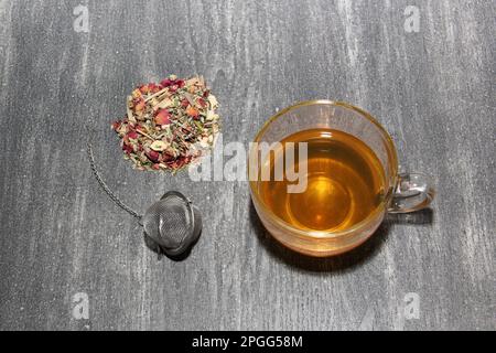 Tools for the preparation of herbal tea: glass cup, infuser, spoon, dehydrated, dried herb and sachets Stock Photo