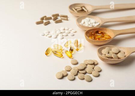Wooden spoons and different dietary supplements on white background. Space for text Stock Photo