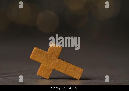 Wooden Christian cross on grey table against blurred lights, space for text Stock Photo