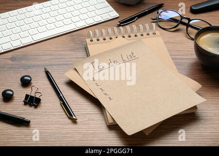 Unfilled To Do list, notebook, pens and cup of coffee on wooden table Stock Photo