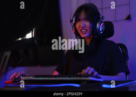 Female cyber hacker gamer in headphone serious face to playing games or hacking programming system. Stock Photo
