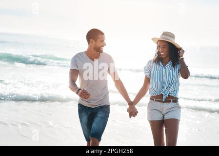 I want to keep strolling through life with you. a young couple walking along the beach. Stock Photo