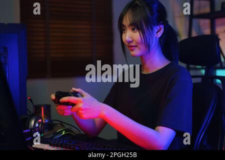Female cyber hacker gamer using controller joystick to playing or streaming games on computer. Stock Photo