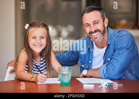 Learning begins at home. a mature man helping his daughter with her homework at home. Stock Photo