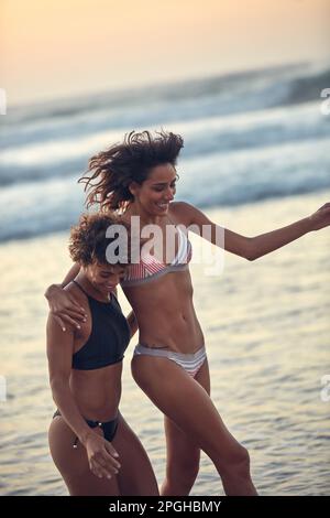 They just cant resist a beach day. two young women enjoying themselves at the beach. Stock Photo