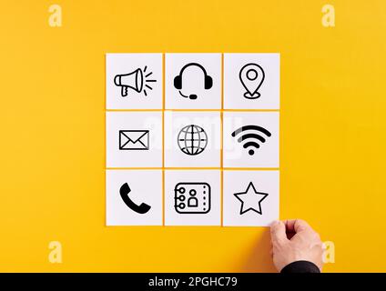 Business marketing, client contact and information. Customer support service. Hand arranges note papers with communication technologies symbols. Stock Photo