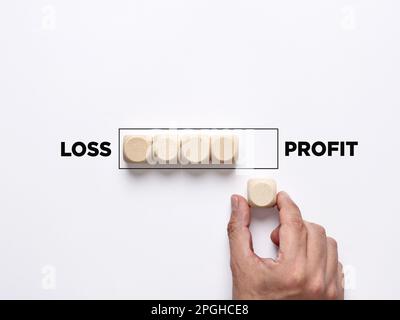 The path to profit in stock exchange. Improving from financial loss to making profit. Business profitability, risk taking. Hand places a wooden cube t Stock Photo