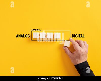 Transition of technology from analog to digital. Technological transformation. Hand places a wooden cube to the loading bar with the words analog and Stock Photo