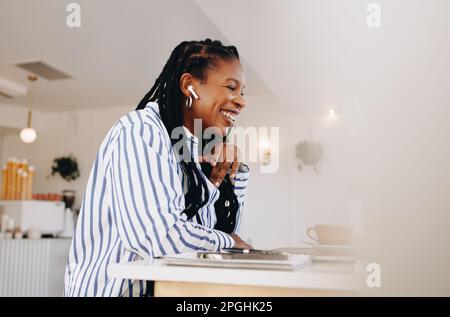Happy young businesswoman attending an online meeting while working in a coffee shop. Smiling young businesswoman having a discussion with a client wh Stock Photo