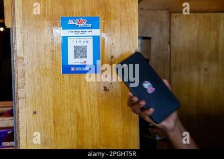 Hand holding mobile phone at QR code for cashless payment in the Critics Poetry Cafe coffeeshop in Trichy, Tamil Nadu,India Stock Photo
