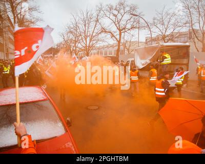 Berlin, Germany - March 06, 2023: Warning strike in front of the gates of the Berliner city cleaning company with orange smoke and waving flags of the Stock Photo