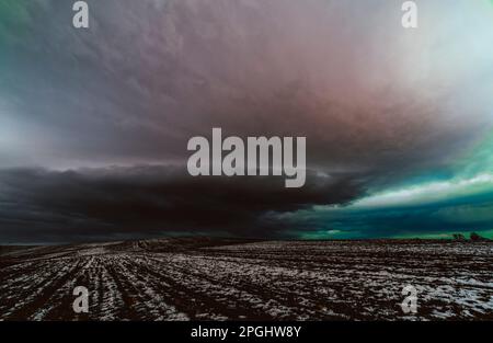 field in winter with cloudy sky in the background Stock Photo