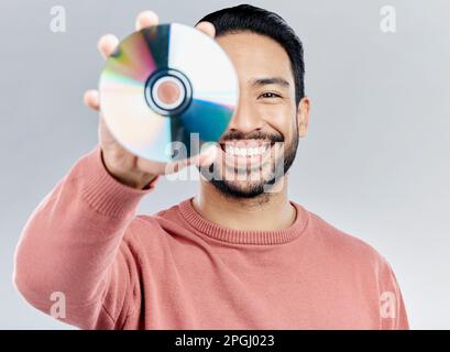Man, holding and compact disc in studio portrait for smile, happiness and technology by white background. Asian model, student and cd in hand for Stock Photo