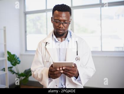 Portrait of a young Black doctor using digital tablet in bright office Stock Photo