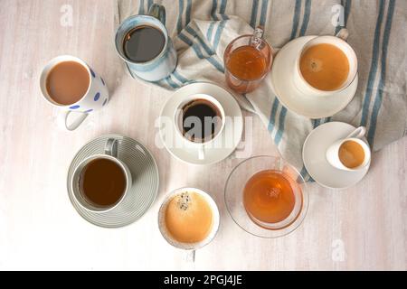 Several different cups and mugs with coffee and tea drinks on a light table with a blue gray towel, high angle view from above, selected focus, narrow Stock Photo