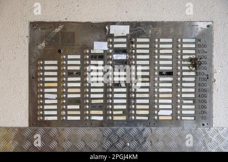 Many door bells without names on a dirty metal plate at the entrance of a large apartment building, concept for housing problems and real estate, sele Stock Photo