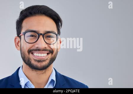 Portrait, happy and excited businessman in studio with glasses, smile and confident on grey background space. Face, isolated and young mexican Stock Photo