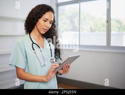 Portrait of a young biracial female doctor, using digital tablet, eHealth Stock Photo