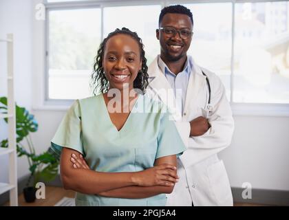 Portrait of two Black doctors, man and woman arms folded posing in clinic Stock Photo