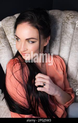 A dark-haired brunette on a Vintage White Chair Stock Photo
