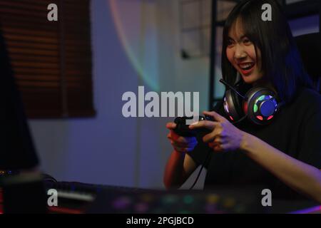 Female cyber hacker gamer using controller joystick to playing games on computer with serious face. Stock Photo