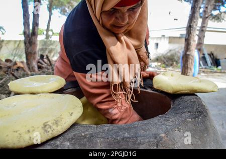 Tunis, Tunisia. 22nd Mar, 2023. Tunis, Tunisia, 22 March 2023. A Tunisian woman bakes the Tabouna bread in a traditional clay oven, before selling it in a market in Tunis. Tabouna is an ancient Tunisian bread made with wheat, semolina, or barley flour and cooked on the walls of a traditional terracotta oven. Tabouna is particularly popular during the Muslim holy month of Ramadan (Credit Image: © Hasan Mrad/IMAGESLIVE via ZUMA Press Wire) EDITORIAL USAGE ONLY! Not for Commercial USAGE! Stock Photo