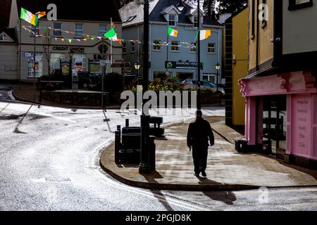 Man walks in the street in Ardara, County Donegal, Ireland. National Republic flags flying for St Patrick's Day. Stock Photo