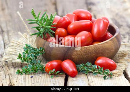 mini roma tomatoes and herbs on wooden background Stock Photo - Alamy
