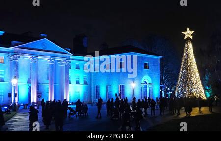 Kenwood House, illuminated for Christmas with tall brightly lit christmas trees and visitors admiring the view Stock Photo