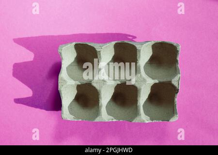 Empty eggs carton box with hard shadows on pink background Stock Photo