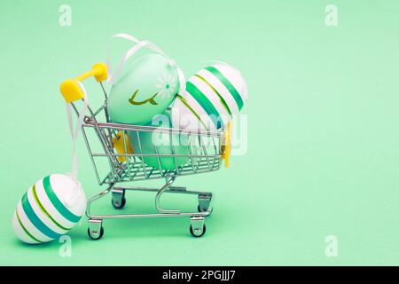 Easter eggs in the shopping cart on a green turquoise background. Stock Photo