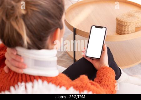 Unrecognizable woman with cervical collar on neck discussing problems with doctor during online session on smartphone Stock Photo