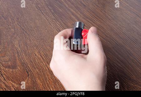 Water ball faucet with red valve in male hand. Brass water tap close up. Shining mini ball valve Stock Photo
