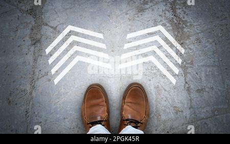 Brown leather shoes and two chalky arrows on asphalt - choice concept Stock Photo