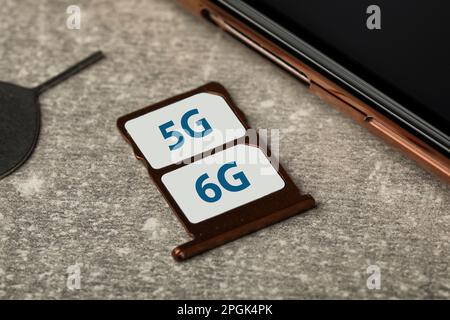 6G and 5G technology, Internet concept. SIM cards in tray with smartphone on grey table, closeup Stock Photo